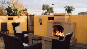 An outdoor patio with wicker furniture, a fire pit, and a yellow wall.