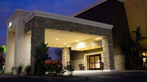 A hotel entrance with a stone facade, a covered entrance area, and a large glass door.