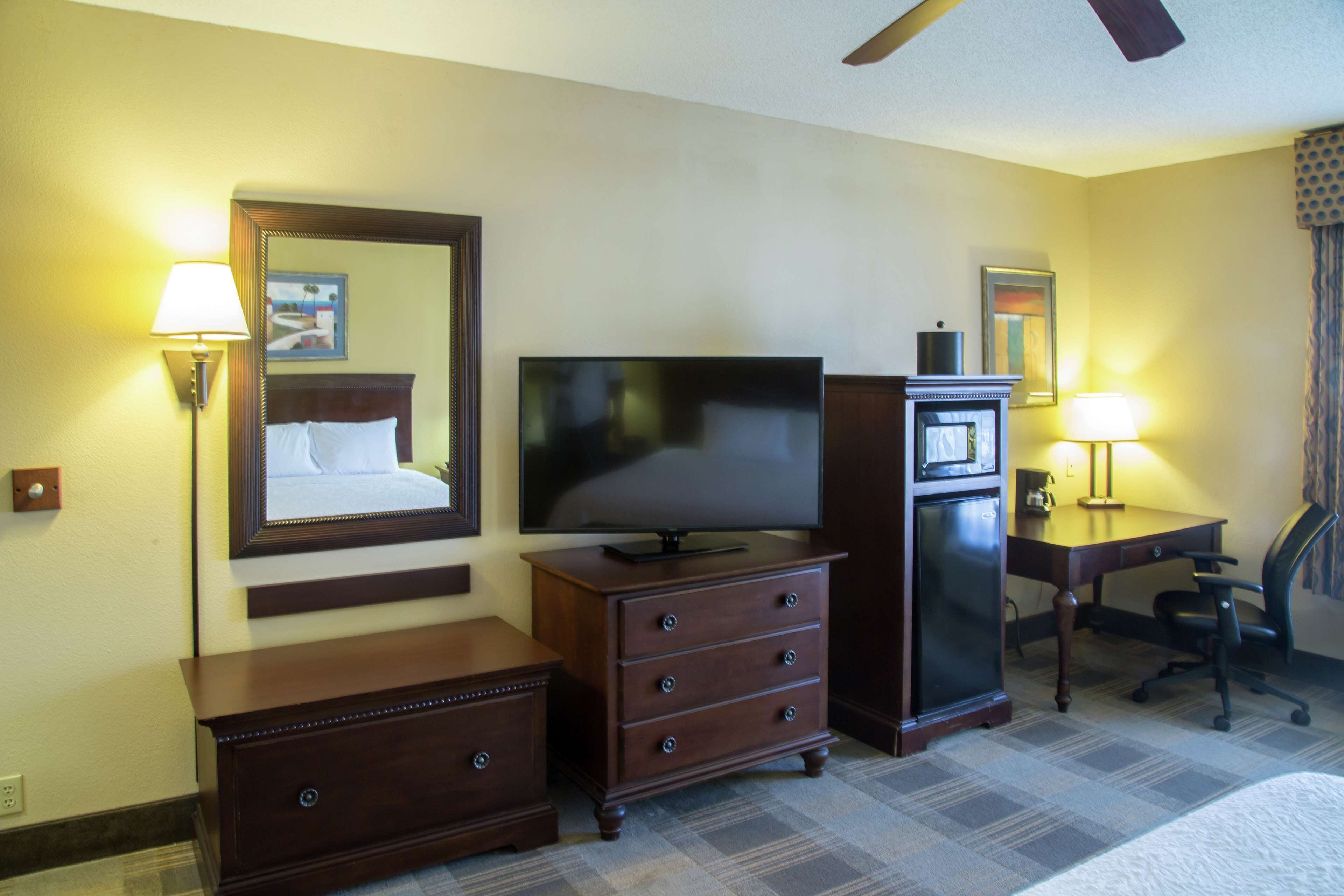A hotel room with a bed, a TV, a dresser, a desk, and a chair.