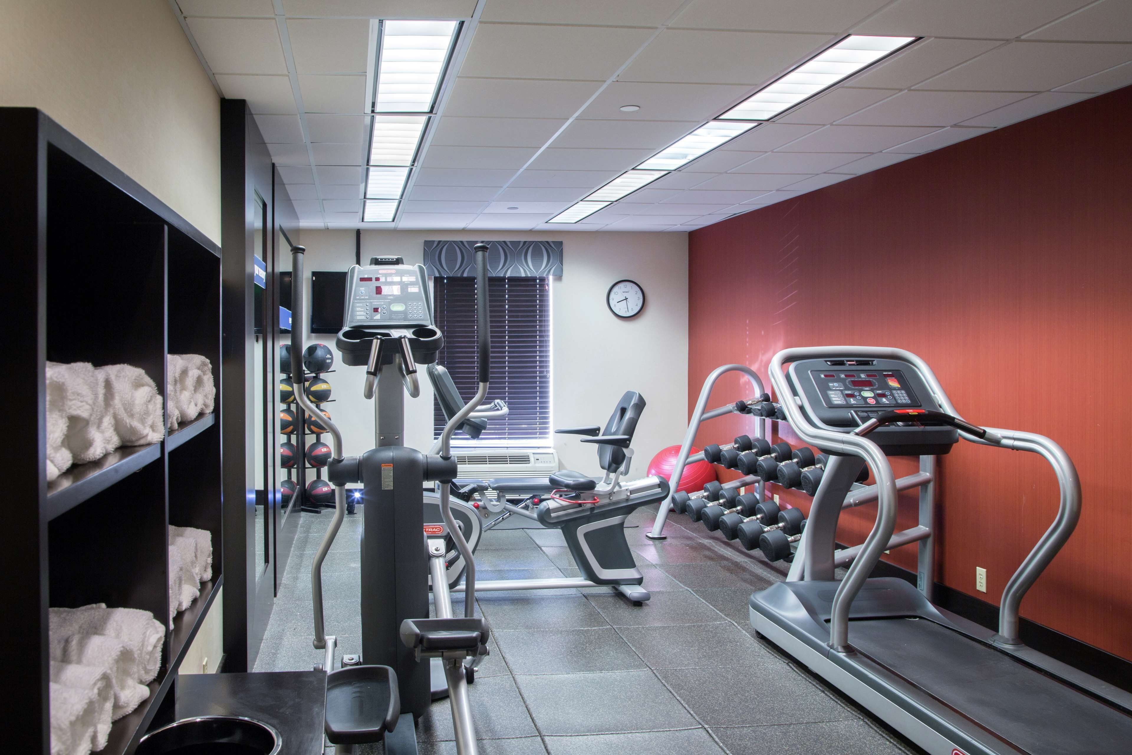 A gym with cardio machines, weight racks, and a treadmill.