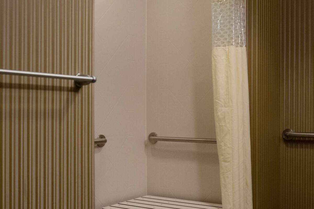 A small, enclosed shower area with a bench, a towel rack, and a shower curtain.