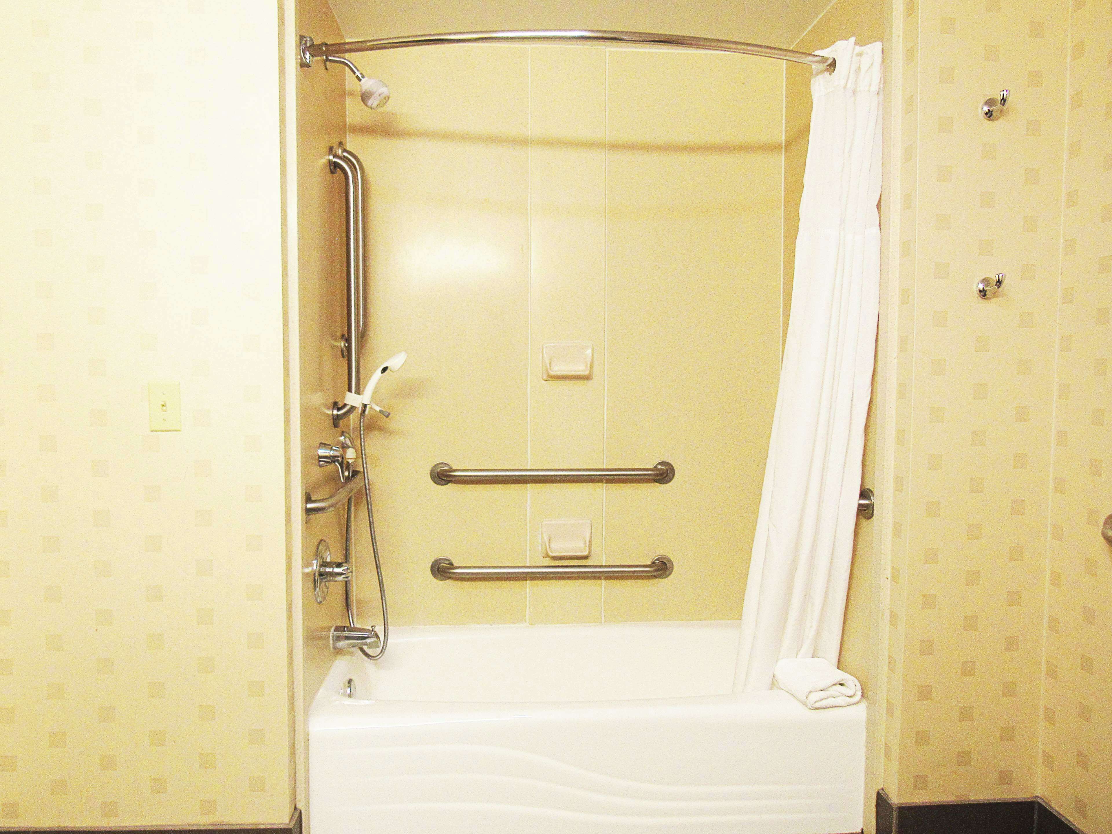 Ein Badezimmer mit einer Badewanne, einer Dusche und einer Haltestange.