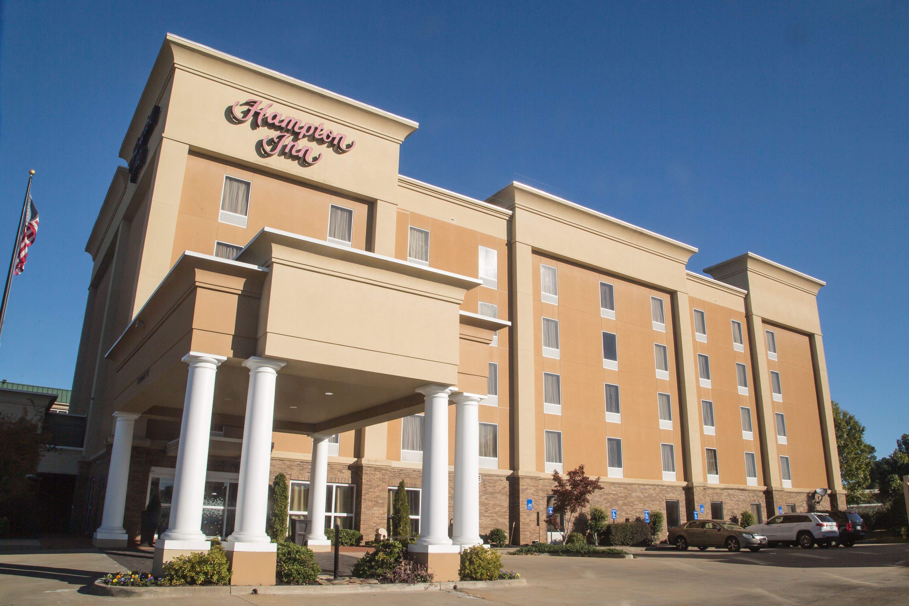 A hotel with a beige facade, multiple floors, and a covered entrance with columns.