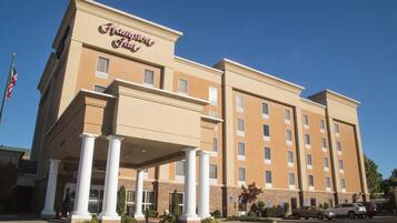 A hotel with a beige facade, multiple floors, and a covered entrance with columns.