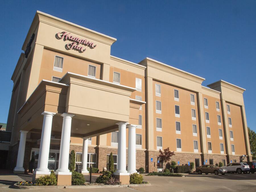 A hotel with a beige facade, multiple floors, and a covered entrance with columns.