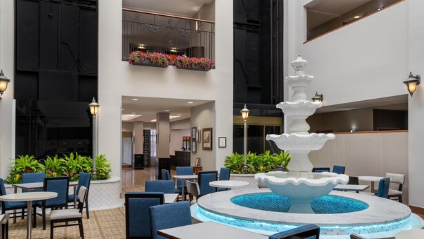 A spacious indoor area with a central fountain, seating arrangements, and a balcony with flower boxes. - Hampton Inn & Suites Rockville Centre (Rockville Centre)