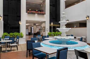 A spacious indoor area with a central fountain, seating arrangements, and a balcony with flower boxes. - Hampton Inn & Suites Rockville Centre (Rockville Centre)