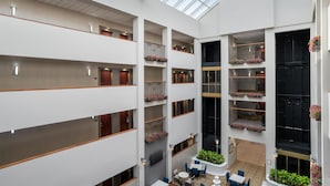 A multi-level atrium with balconies, indoor plants, and a central seating area. - Hampton Inn & Suites Rockville Centre (Rockville Centre)