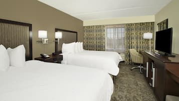 Ein Hotelzimmer mit zwei Betten, einem Schreibtisch, einem Fernseher, einem Telefon und einer Lampe.