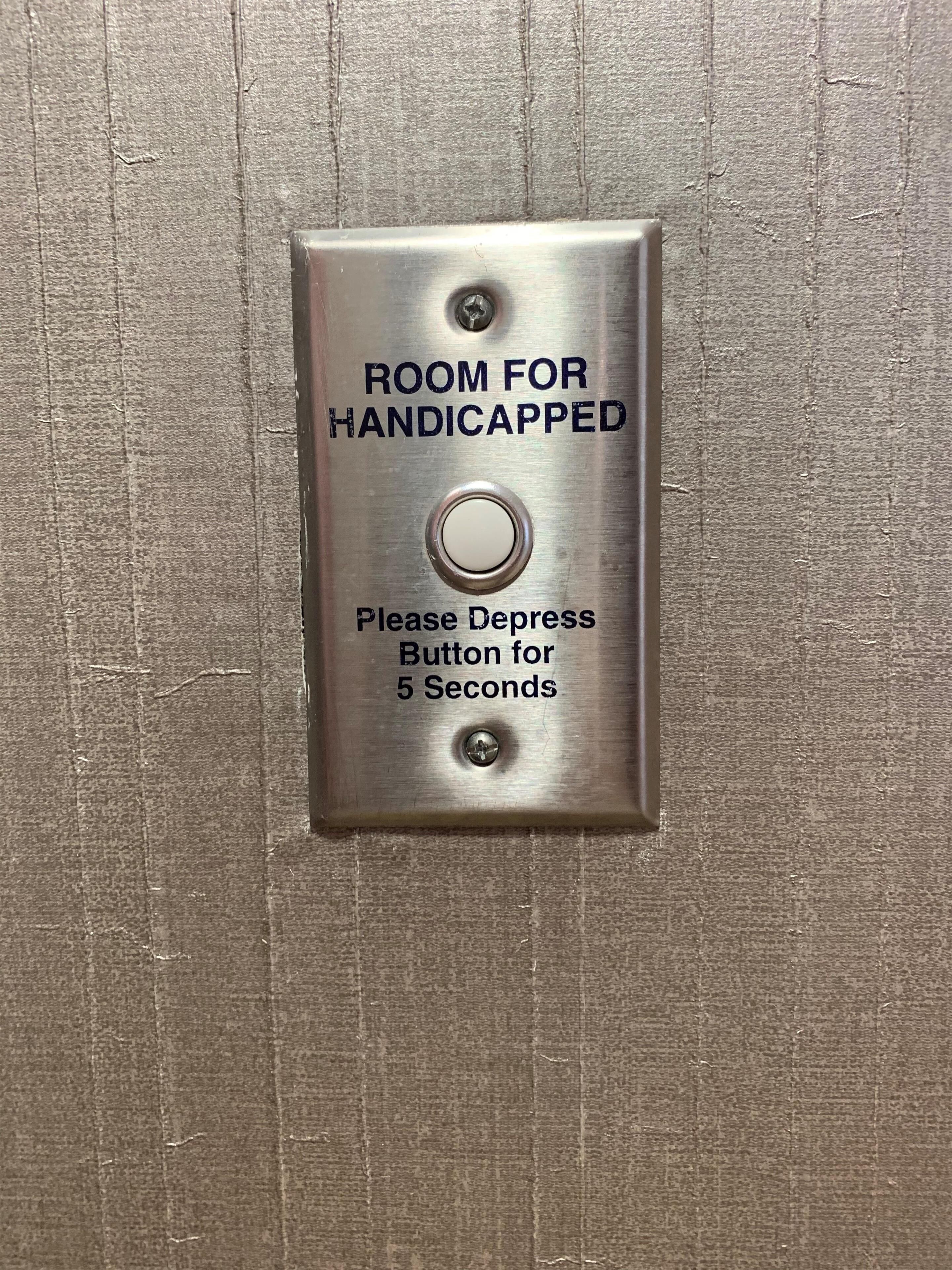 A sign indicating a room for handicapped individuals with a button to depress for 5 seconds.