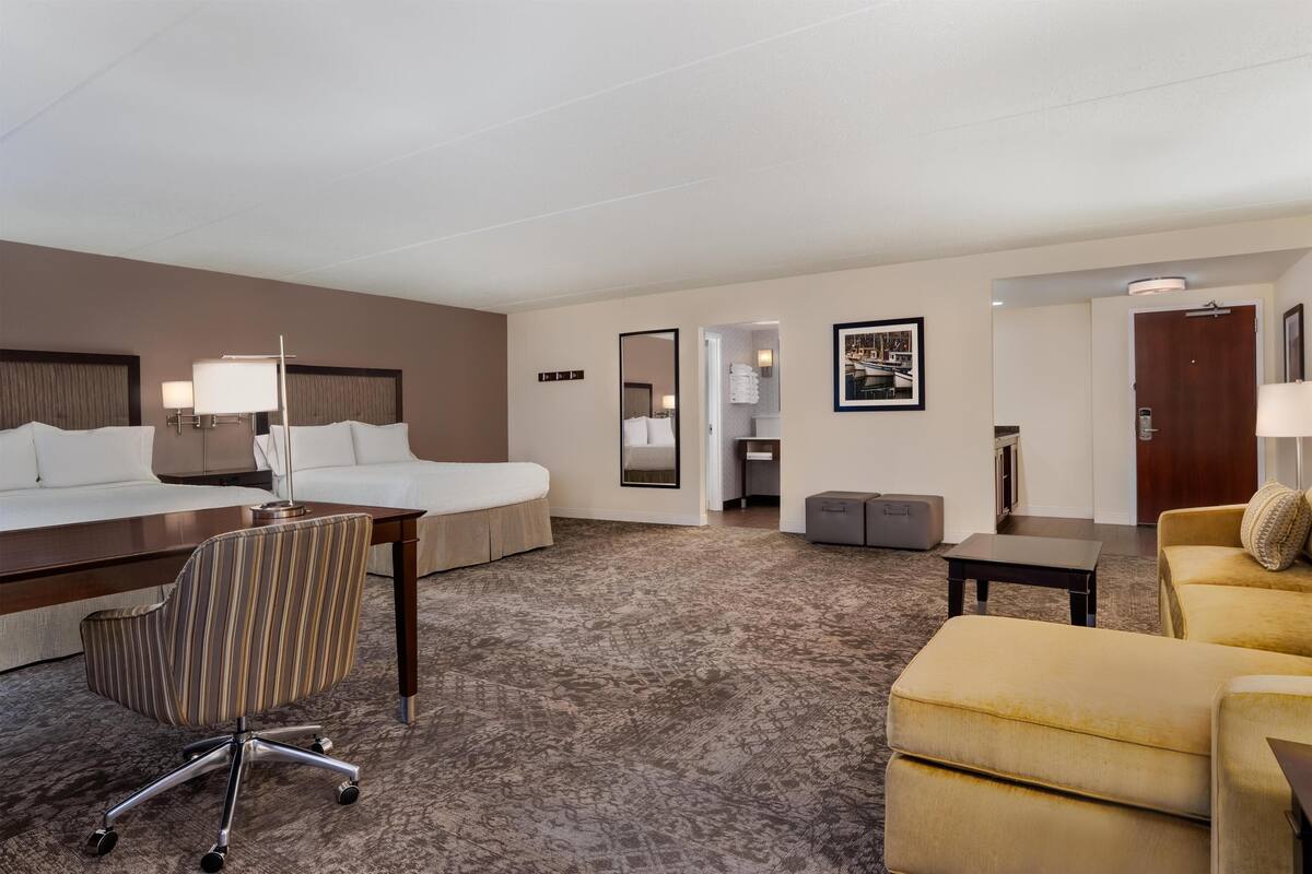 Ett hotellrum med en säng, ett skrivbord, en stol, en soffa och ett litet bord.