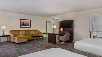 Una habitación de hotel con cama, escritorio, sofá, televisión y baño.