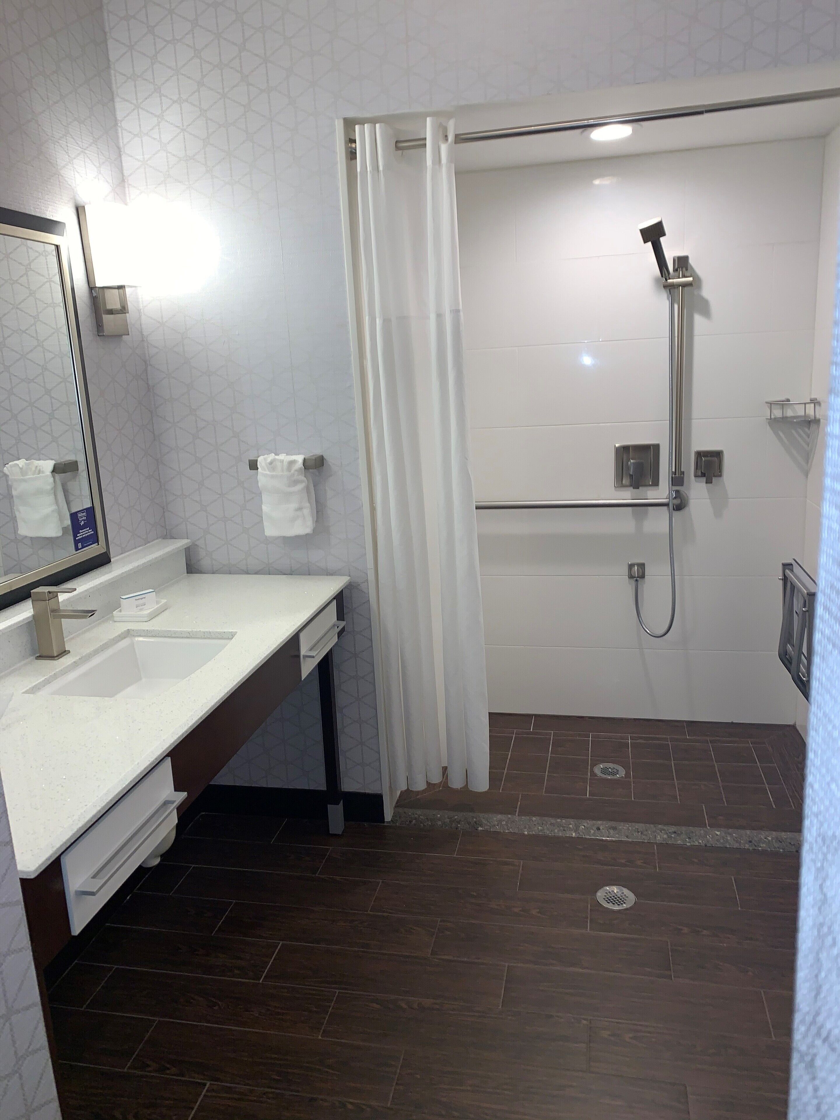 A modern bathroom with a white sink, mirror, and shower area.