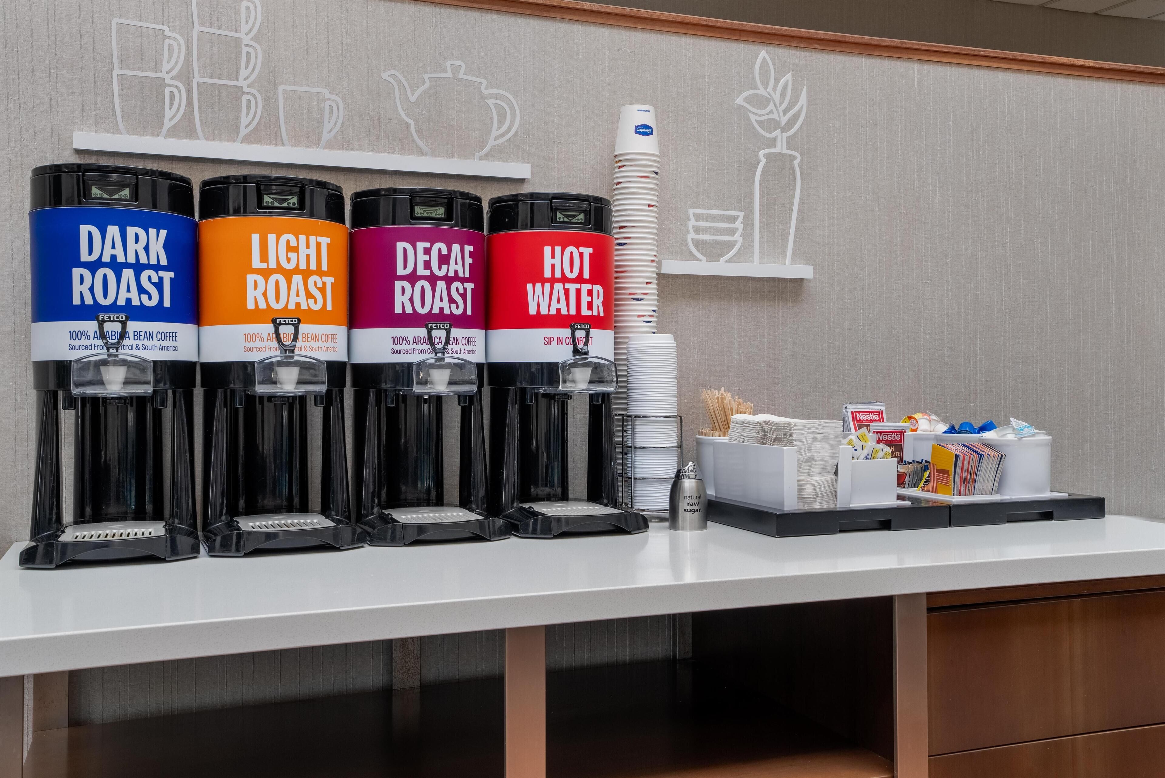 Eine Kaffeestation mit vier Spendern, beschriftet mit 