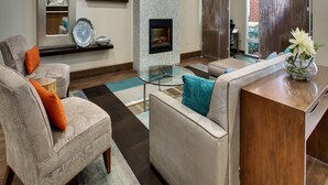 A modern living room with a fireplace, a flat-screen TV, and a glass coffee table. - Hampton Inn Shreveport Airport (Shreveport)