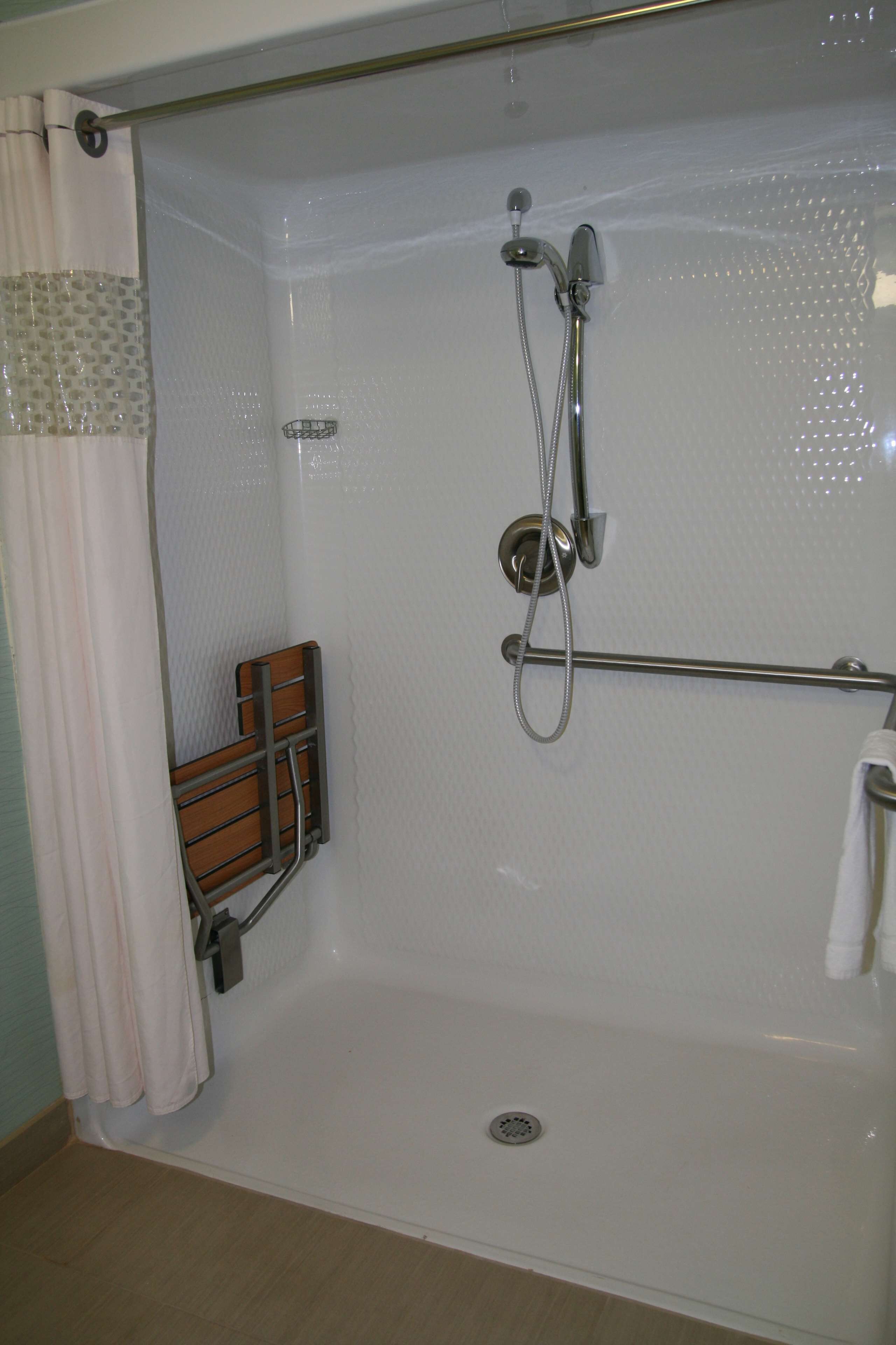 Une douche à l’italienne avec une porte en verre, un pommeau de douche, un flexible de douche et un porte-serviettes.