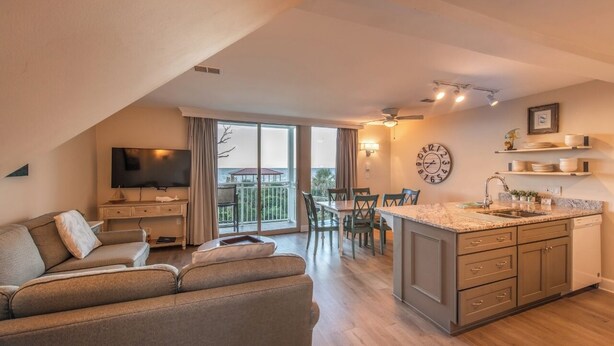 A modern apartment with a living room, dining area, kitchen, and balcony. - Villas By the Sea Resort & Conference Center (Jekyll Island)