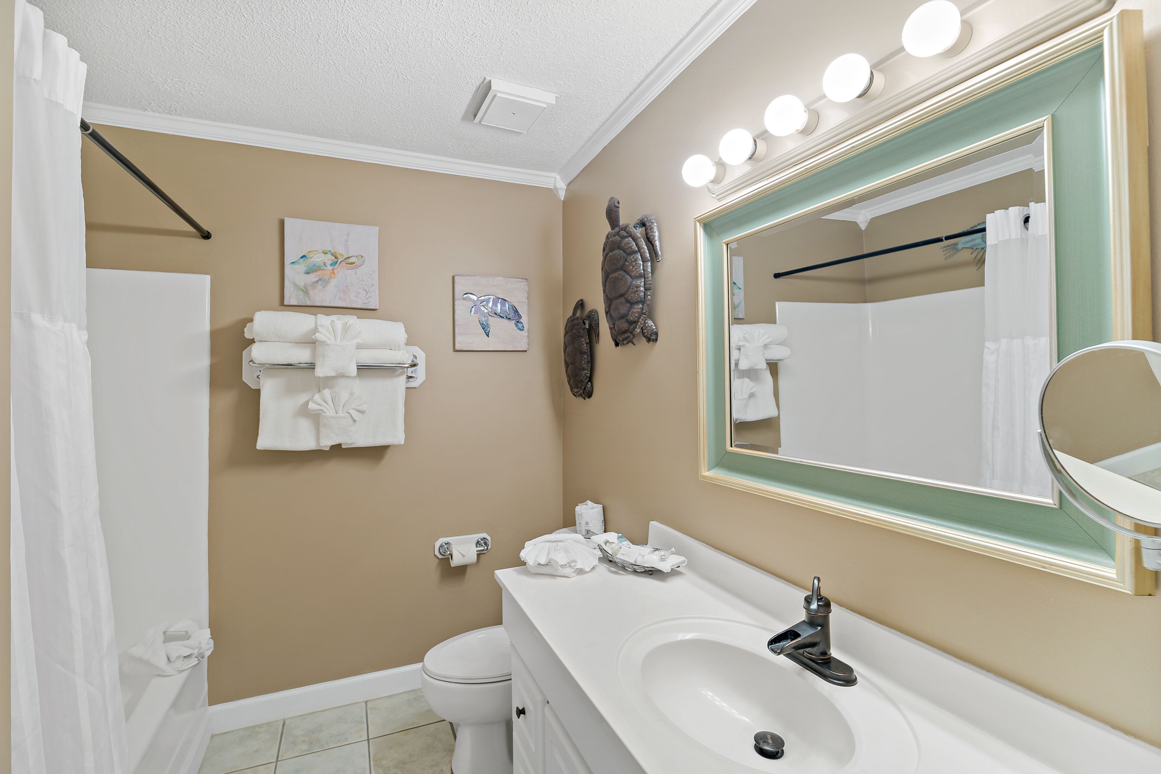 Une salle de bain avec un lavabo blanc, un miroir et un porte-serviettes. Deux serviettes sont accrochées au mur, et il y a un rideau de douche.