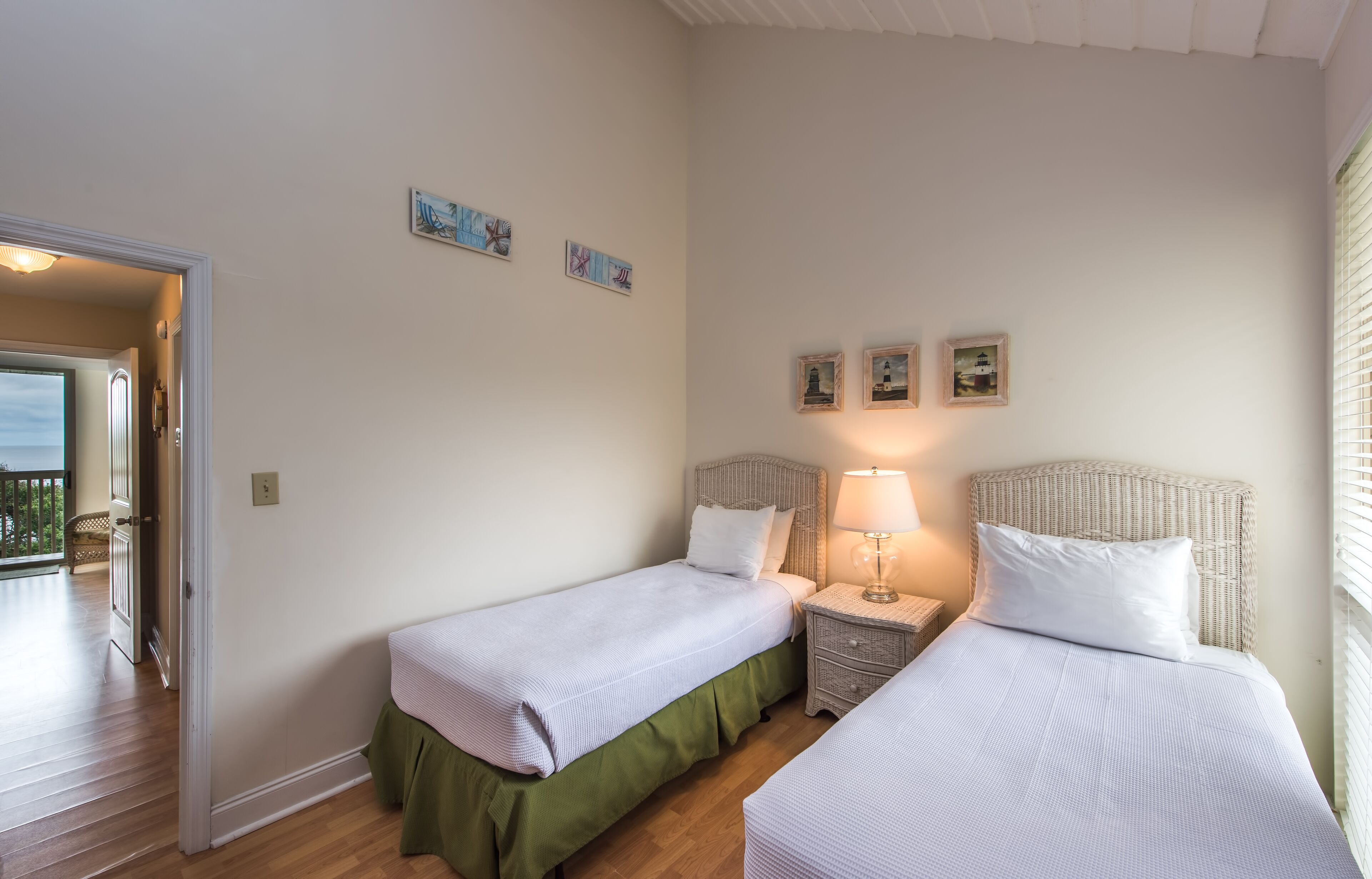 A bedroom with two single beds, a nightstand with a lamp, and a door leading to a balcony.