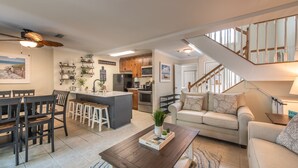 A modern kitchen with wooden cabinets, a central island, and a dining area with a table and chairs. - Villas By the Sea Resort & Conference Center (Jekyll Island)
