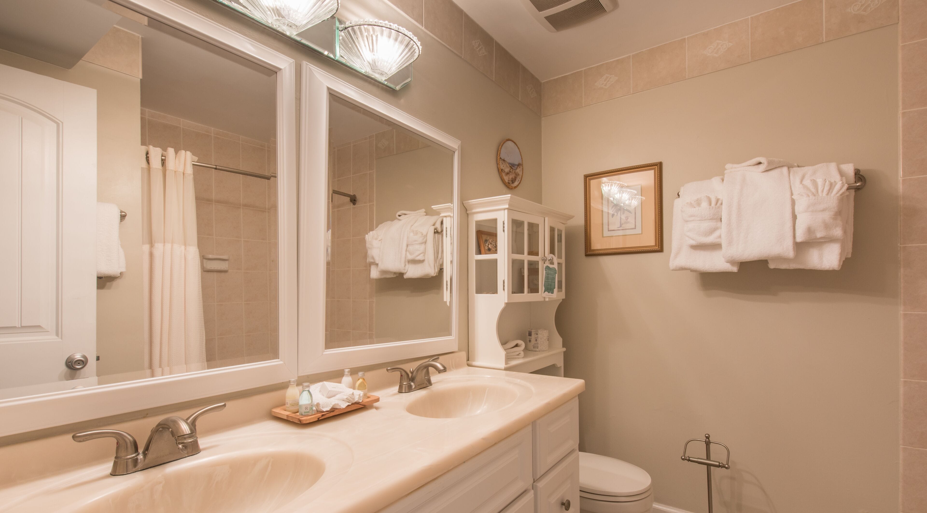 A bathroom with two sinks, a large mirror, a toilet, and a towel rack.