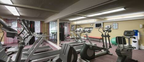 A gym with various exercise equipment, including treadmills, elliptical machines, and a stationary bike.