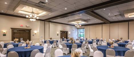 A conference room with multiple round tables, white chairs, and blue tablecloths.