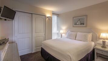 A neatly arranged bedroom with a bed, bedside lamps, a television mounted on the wall, and a framed picture on the wall.