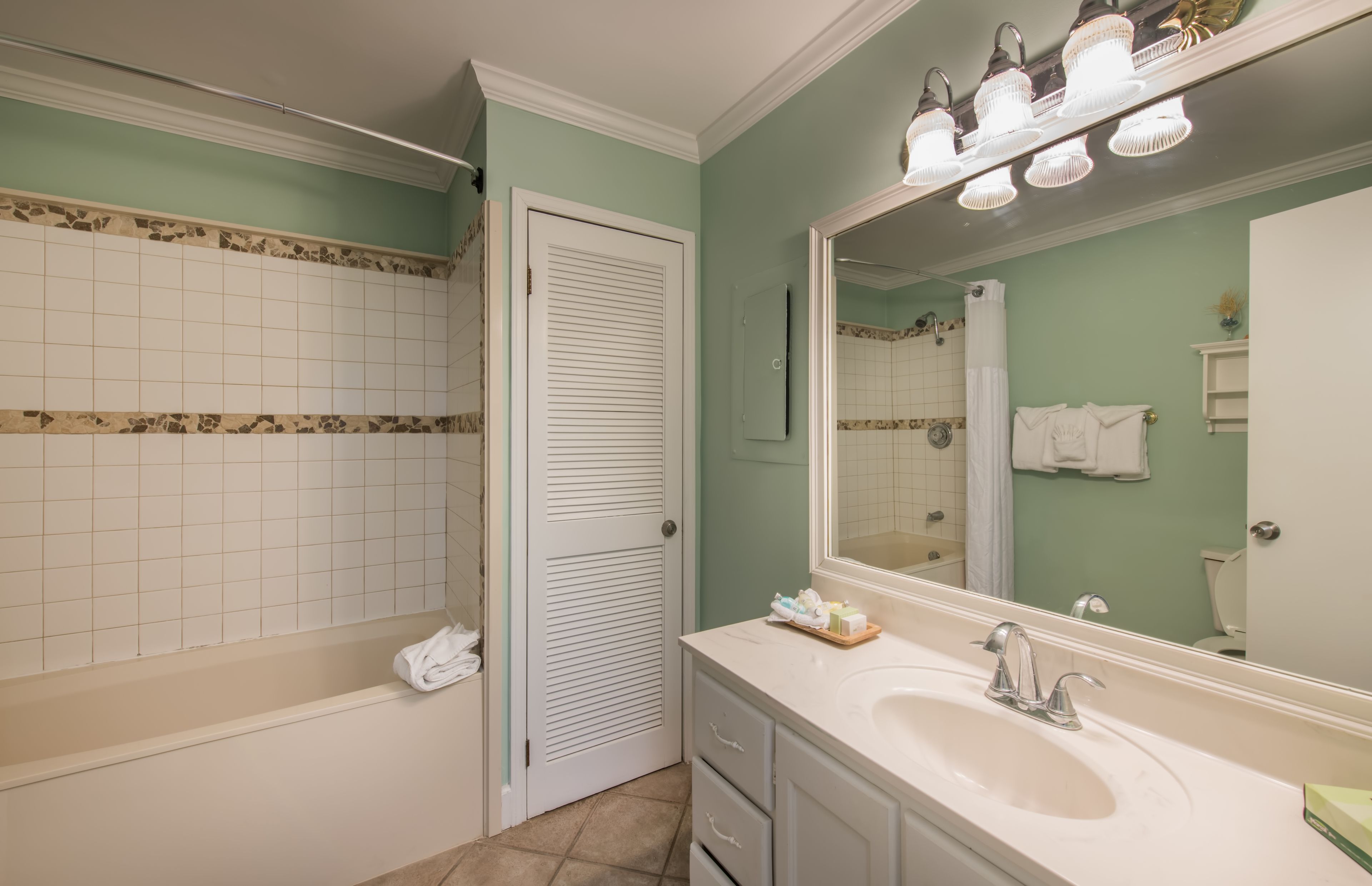 Une salle de bain avec un lavabo blanc, un miroir et des murs carrelés.