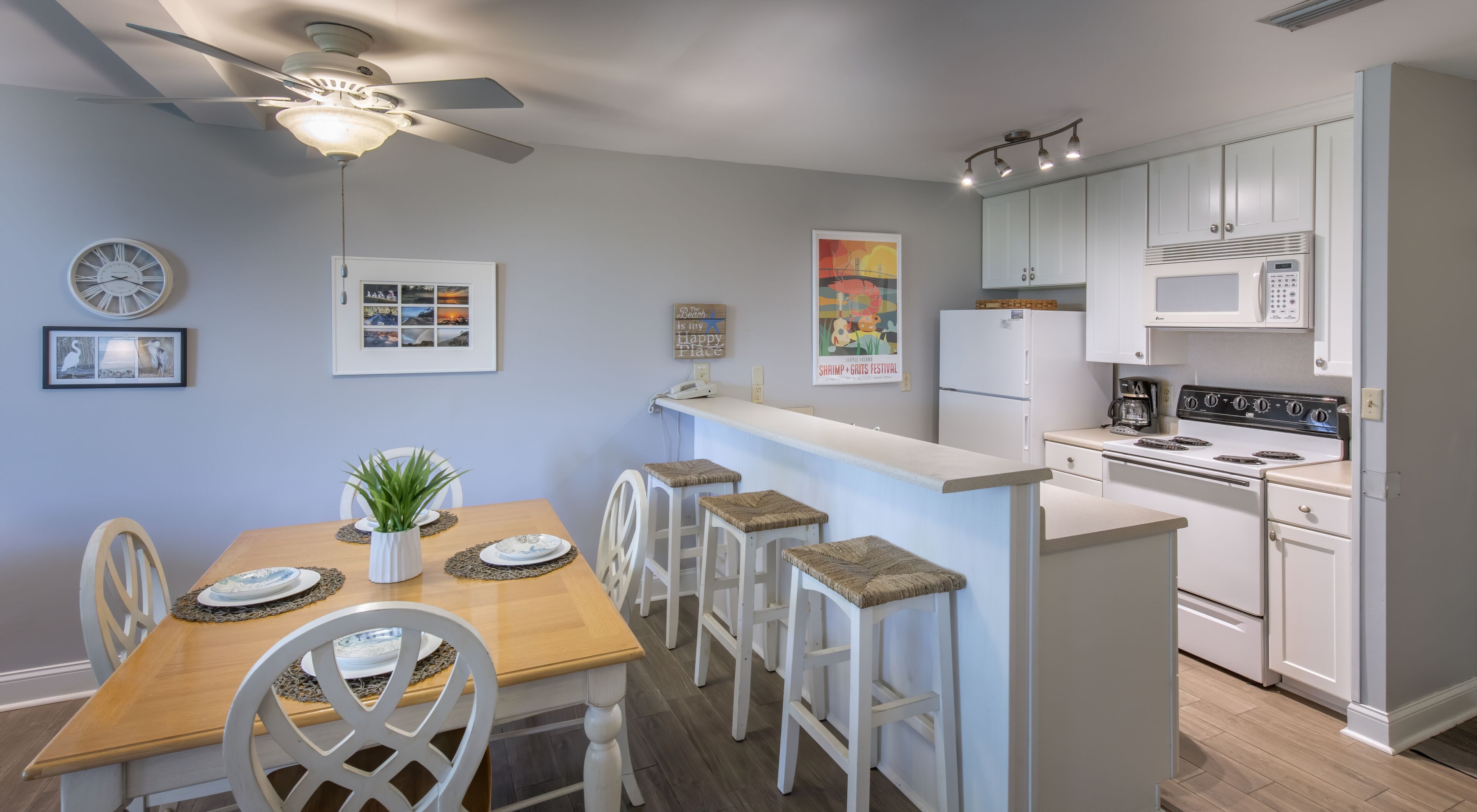 A compact kitchen with a central island, white cabinetry, and a ceiling fan.