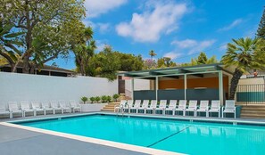 A swimming pool with white lounge chairs and a covered seating area. - Orange Tree Inn (Santa Barbara)