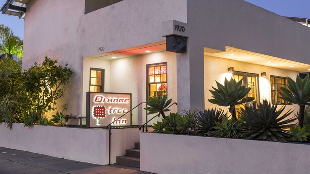 Un hôtel moderne dont la façade porte une enseigne indiquant « Orange Tree Inn » et le numéro « 1920 ».