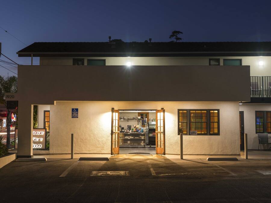L’entrée d’un hôtel avec un parking, une enseigne bien visible indiquant « Orange Tree Inn », et une voiture garée à l’extérieur.