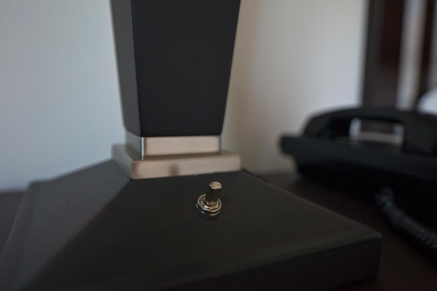 Un objeto negro y rectangular con un componente metálico en la parte superior, posiblemente un mueble o equipo.