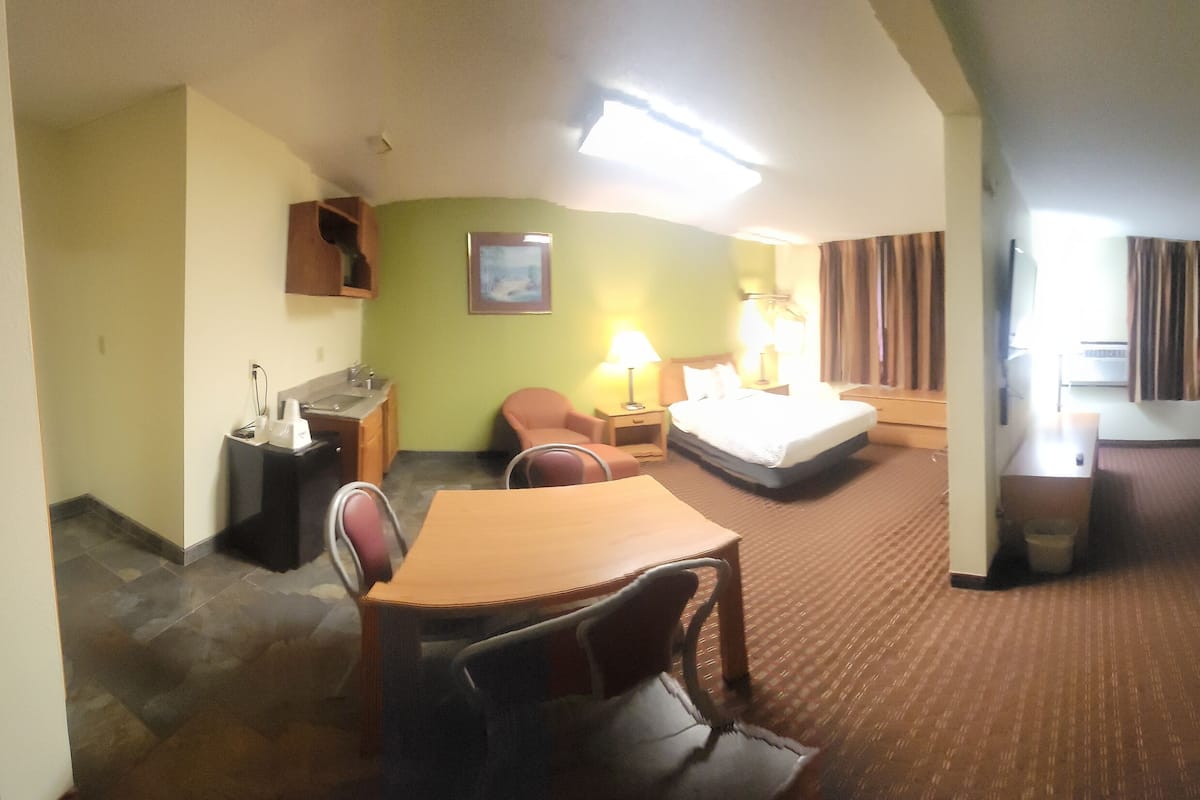 A hotel room with a bed, a desk, a chair, a sofa, and a small table.