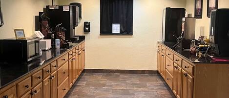 A kitchen with wooden cabinets, a black countertop, and a tiled floor.