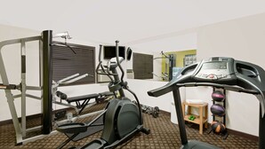 Une salle de sport équipée de divers appareils, notamment un tapis de course, un vélo elliptique et des appareils de musculation.