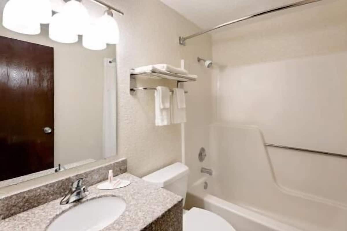 A bathroom with a sink, mirror, towel rack, and a shower area.