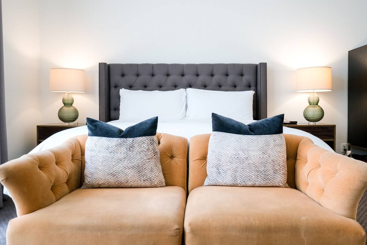A hotel room with a large bed, two armchairs, and two bedside lamps.