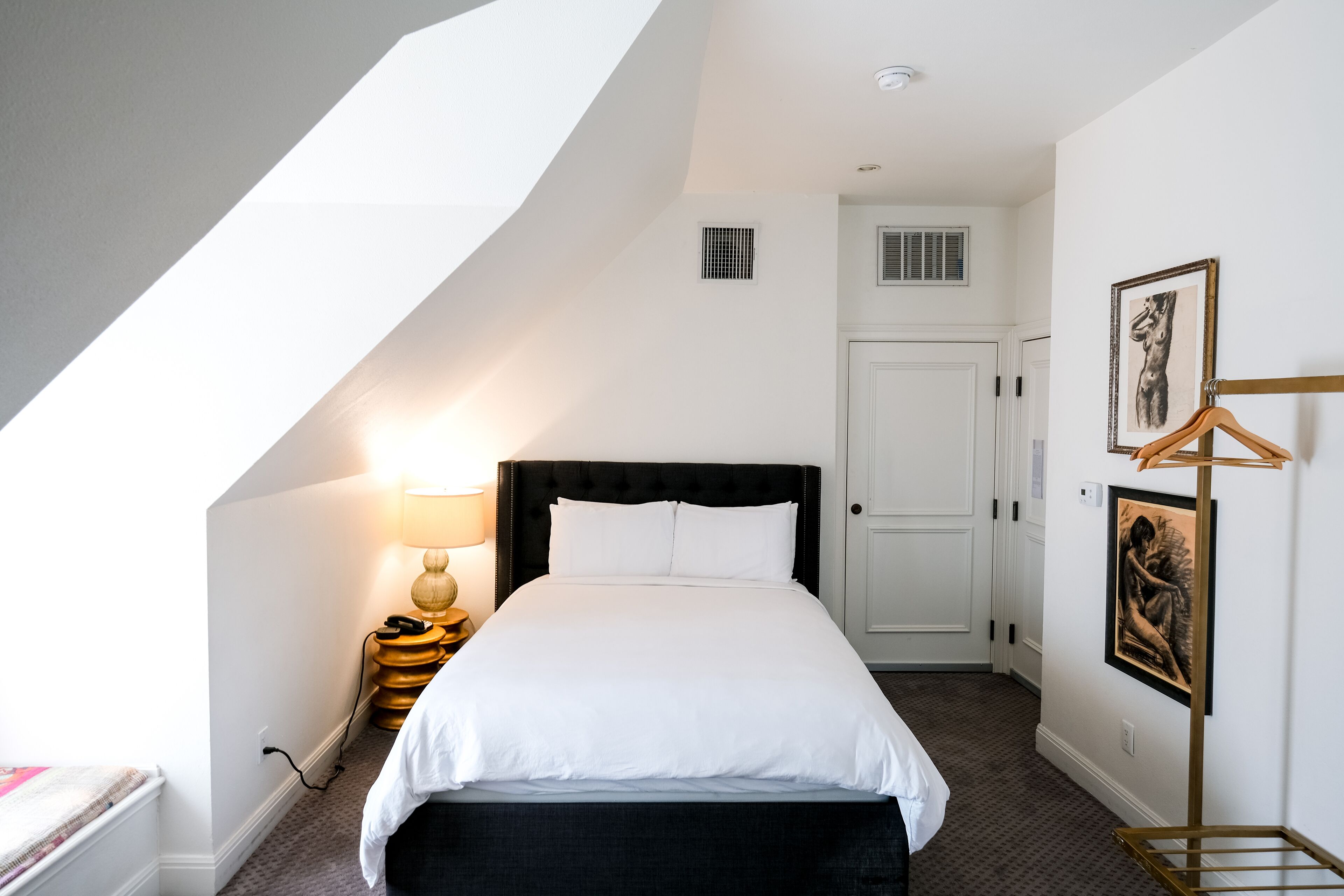 A bedroom with a bed, a bedside lamp, a wardrobe, and a framed picture on the wall.
