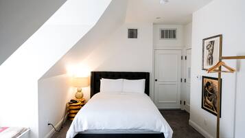 A bedroom with a bed, a bedside lamp, a wardrobe, and a framed picture on the wall.
