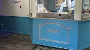 Un'area reception di un hotel con arredamento nei toni del blu e del bianco, un cartello che indica una fontana di ghiaccio al secondo piano e un segnale che vieta l'accesso agli animali domestici.