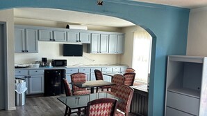 Una cucina moderna con mobili bianchi, un'area pranzo con sedie a fantasia e una TV a incasso.