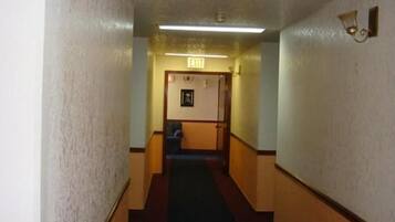 A narrow hallway with a carpeted floor, wooden walls, and a door at the end.