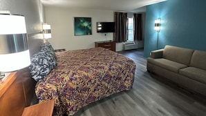 Una camera d'albergo con un letto grande, un divano, una TV e una scrivania.