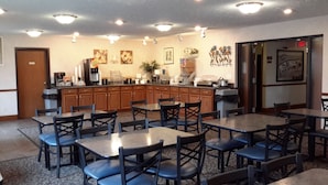 A restaurant with multiple tables and chairs, a kitchen area, and various wall decorations. - Super 8 by Wyndham Greenfield (Greenfield)