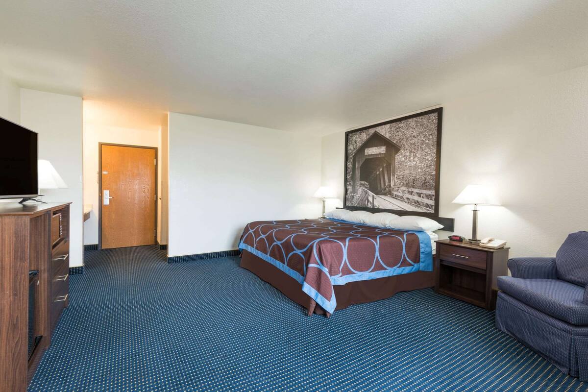 Ein Hotelzimmer mit Bett, Stuhl, Schreibtisch und Fernseher.