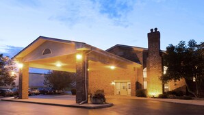 A hotel entrance with a covered parking area, brick facade, and a chimney. - Super 8 by Wyndham Greenfield (Greenfield)