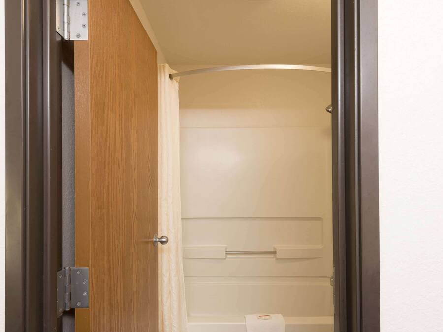 A bathroom with a shower, a towel rack, and a toilet paper roll.