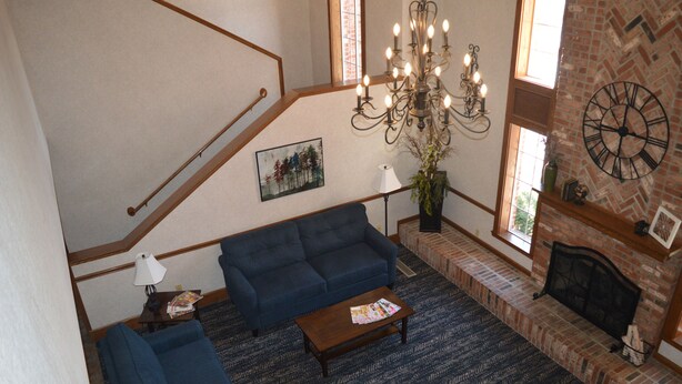 A spacious living area with a blue sofa, a wooden coffee table, and a fireplace. - Super 8 by Wyndham Greenfield (Greenfield)